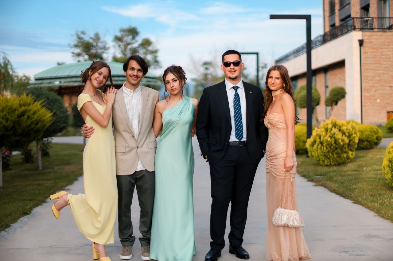 our-story Group of young adults posing in stylish formal wear outdoors, exuding elegance and sophistication.