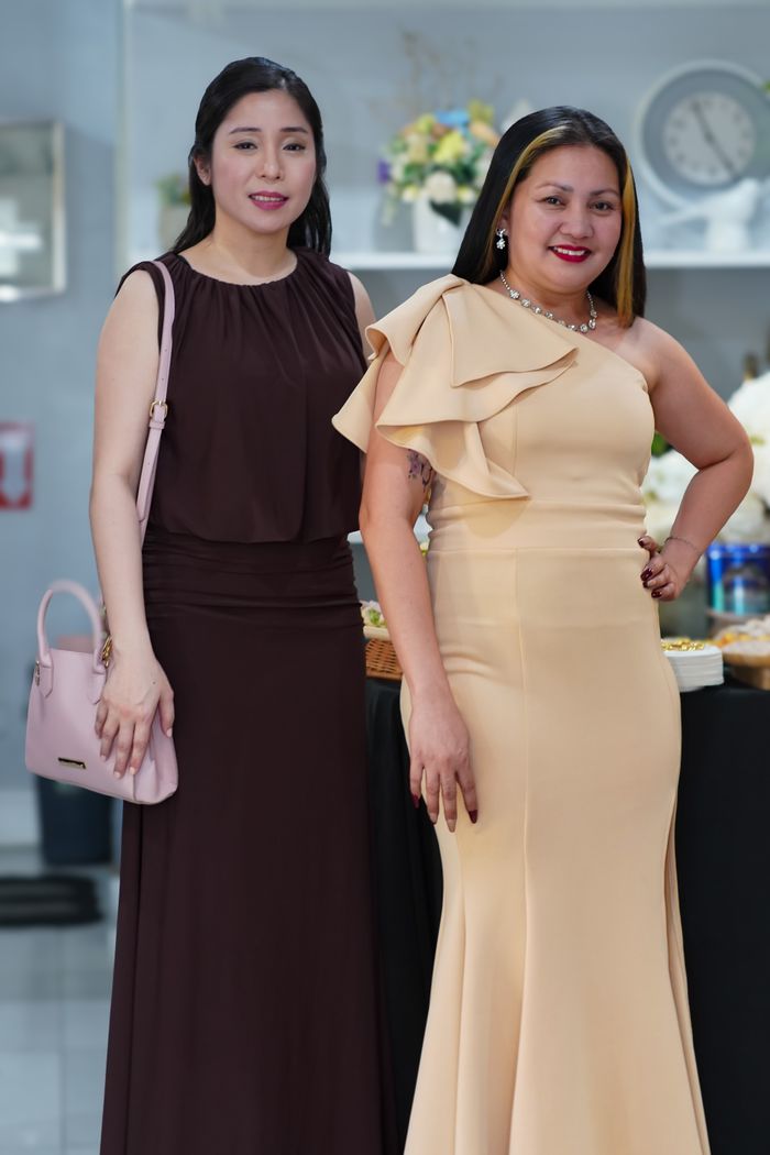about-us Two women in elegant dresses pose at an indoor event. Perfect for fashion and lifestyle themes.